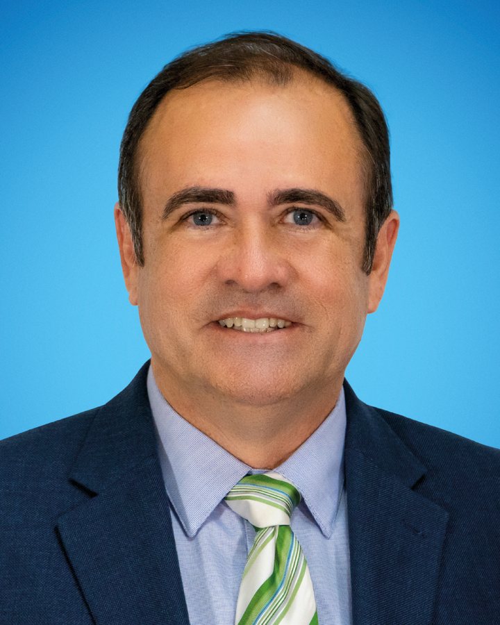 Retrato oficial do vereador Afonso Neto, sorrindo, de terno azul e gravata listrada verde